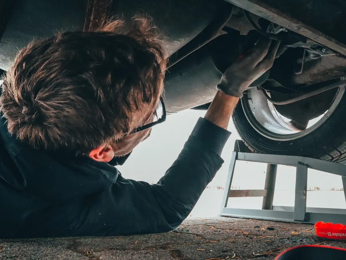 Mechanic inspecting vehicle underside for maintenance and repairs, highlighting expertise in auto servicing.